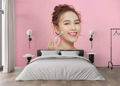 Close-up of a young cute girl holding brush in her hand and applying makeup. Wall mural