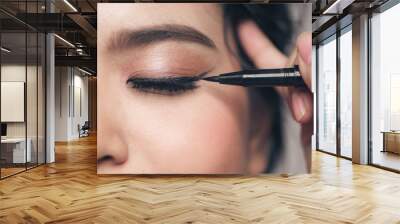 Close-up portrait of beautiful girl touching black mascara to her lashes Wall mural