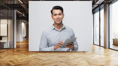 Handsome young Asian man using pad on white background. Wall mural