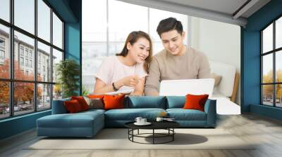 Happy businesswoman and businessman using laptop at workplace in office Wall mural