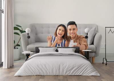 Happy young couple relaxing and watching TV at home. Wall mural