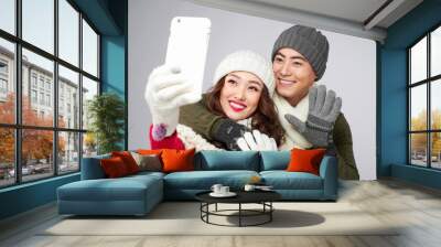 Happy young lovers in knitted woolen clothing hugging and taking selfie picture. Wall mural