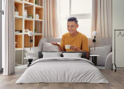 happy young Man sitting in sofa and using laptop Wall mural