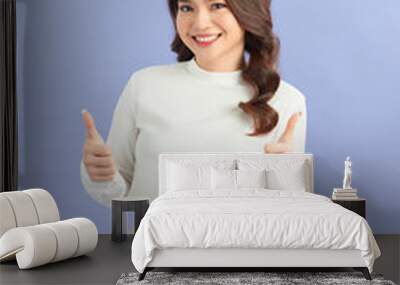 Image of cheerful young lady standing isolated over purple background. Looking camera showing thumbs up. Wall mural