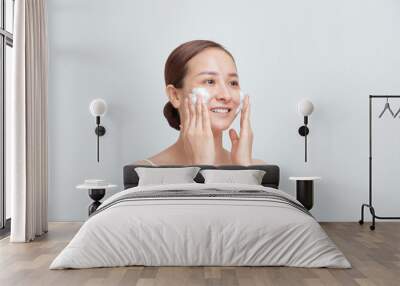 Portrait of cheerful laughing woman applying foam for washing on her face. Wall mural