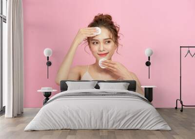 Portrait of young beautiful woman with healthy glow perfect smooth skin removing make up with cotton pad. Wall mural