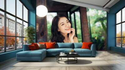 pretty happy asian woman watching on herself in a big mirror at home. Wall mural