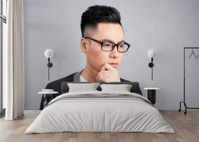 Studio shot of young Asian man thinking while wearing eyeglasses Wall mural