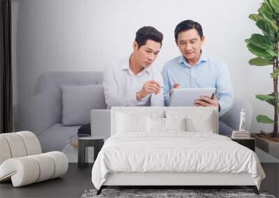 Two confident young businesspeople using a laptop discuss information while sitting on a sofa in a modern office Wall mural