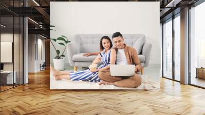 Young Asian couple shopping online at laptop computer at home Wall mural