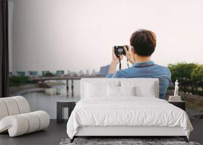 Young asian man tourist taking photos outdoor in the city Wall mural