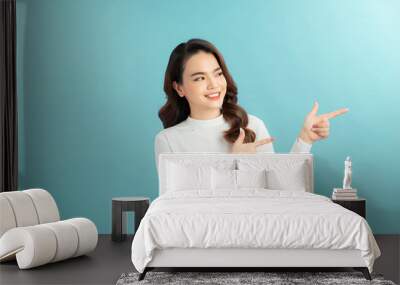 Young asian woman over isolated background smiling and looking at the camera pointing with two hands and fingers to the side. Wall mural