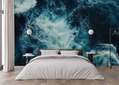 Aerial view of ocean waves crashing against the shore with deep blue water creating a dynamic and peaceful coastal scene Wall mural