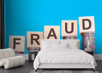 wooden cubes with the word Fraud on money pile of coins, business concept Wall mural