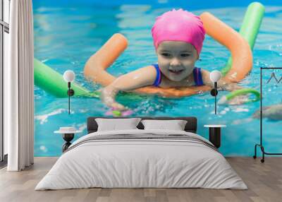 A little girl of European appearance floating in the pool on inflatable toy Wall mural