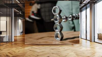 A person is meticulously stacking nuts on top of one another skillfully on a wellcrafted wooden table, creating an interesting arrangement Wall mural