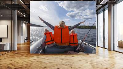 Girl in a life jacket floating on the boat with his hands up. Children in life jackets sitting next Wall mural