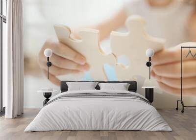 child girl holding two big wooden puzzle pieces. hands connecting jigsaw puzzle. close up photo with Wall mural