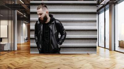 modern young bearded man in black style clothes standing in around urban background. Wall mural