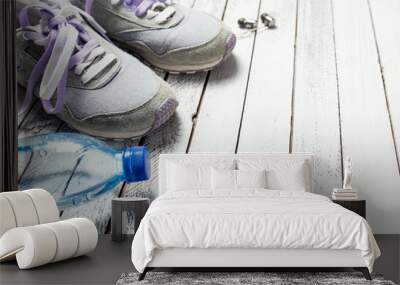 Pair of sport shoes, water bottle and earphones on white wooden Wall mural