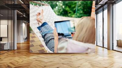 Woman using tablet computer while relaxing in a hammock Wall mural