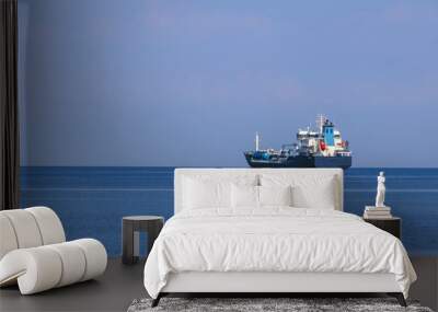 sea cargo ship at sea against  a background of the sea horizon, and a cloudless sky Wall mural