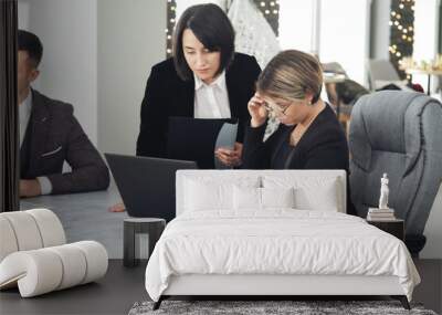 Two young business women in the office, analyzing information looking into a laptop Wall mural