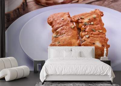 Deep-fried battered cod fillets, in a white plate next to onions and bread on a wooden background. Close-up Wall mural