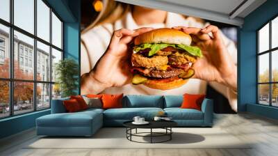 .Young woman eating burger in restaurant Wall mural