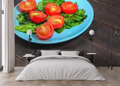 Tomatoes and greens spinach on a blue plate Wall mural