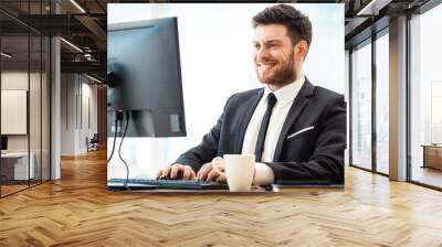 Young businessman in office sitting at his desk Wall mural