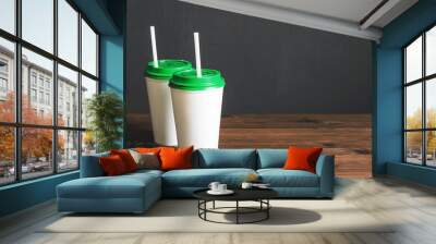 two white plastic coffee cups with a green lid on a wooden table with scattered coffee beans, copy space Wall mural