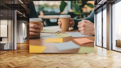 A mentor gives personal development advice to a mentee as they discuss a career advancement strategy over coffee in a bright, stylish cafe, surrounded by notes and goal sheets. Wall mural