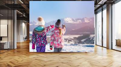 Back view of children standing on rural roadway in snow looking at mountain range in sunshine Wall mural