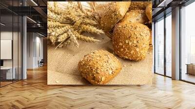 Freshly baked bread. Fresh loaf of rustic traditional bread with wheat grain ear or spike plant on linen texture background. Rye bakery with crusty loaves and crumbs. Healthy Food concept. Wall mural