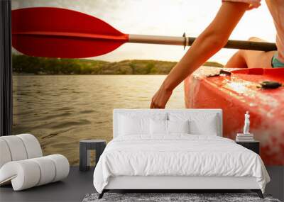 Young Woman Playing with Water while Sitting in Kayak on Beautiful River or Lake at Sunset. Close up of Female Hand. Wall mural