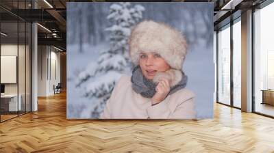 Winter portrait of a woman in white coat during snowfall in a park Wall mural