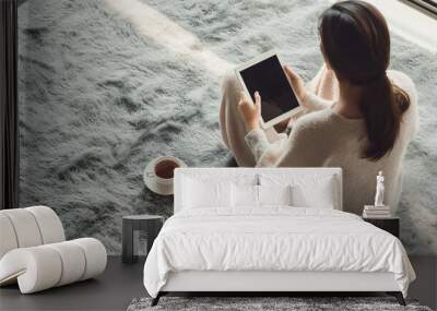 Woman enjoying a serene morning, dressed in soft pastel beige, seated on a plush grey carpet, sipping coffee with a tablet and mobile phone placed nearby, blank screens for copy sp Wall mural