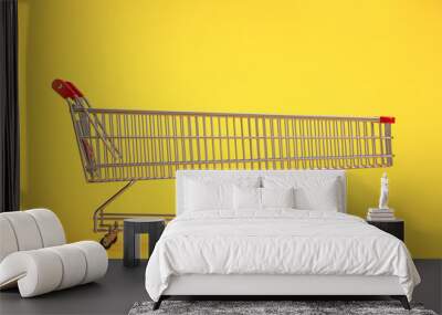 Long shopping cart on yellow background. Sales an discounts concept. Wall mural