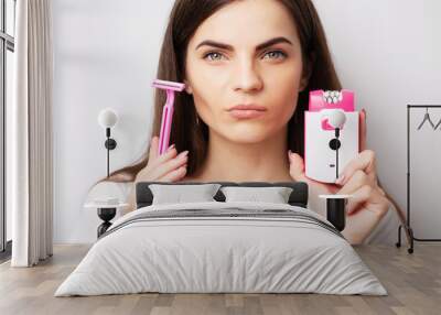 Care concept, woman holding epilator and razor near face to remove hair Wall mural