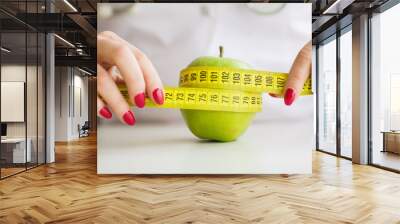 Diet. Woman holding a green apple and measuring Wall mural