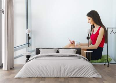 Home Light Office. Business Woman Works on Computer at Home. Dressed in Red Jacket and Black Skirt, Sitting on Table and Speaking by Phone. High Resolution Wall mural