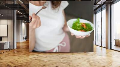 Portrait of beautiful young woman eating diet salad at home. Wall mural