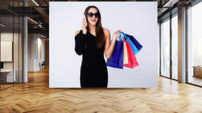 Shopping. Woman holding colored bags on light background in black friday holiday Wall mural