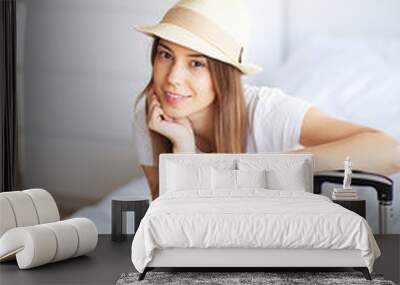 Woman legs raised up on the baggage, Young woman at home laying in bed. The white bedroom Wall mural