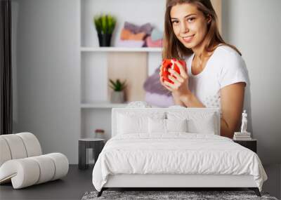 Young woman in comfortable pajamas sitting on the table in her room Wall mural