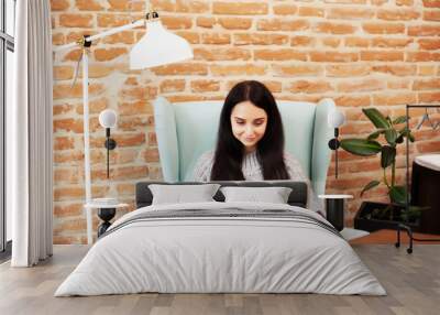 Young woman working on laptop computer while sitting at the living room Wall mural