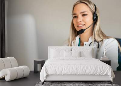 Smiling Attractive Young Woman Wearing Headset and stethoscope Near Her Computer Monitor. Health care customer support concept or ambulance dispatcher.  Wall mural