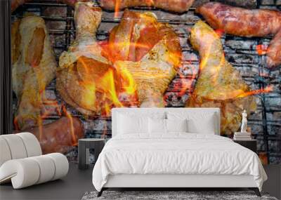 Chicken legs and meat sausages on an iron barbecue net over the fire. Cooking over a fire. Grill mesh. Chicken and meat sausages. Healthy eating. Food in nature. Menu of dishes. Background image. Wall mural