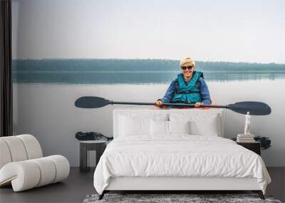 Woman in sunglasses enjoying the lake from red kayak Wall mural